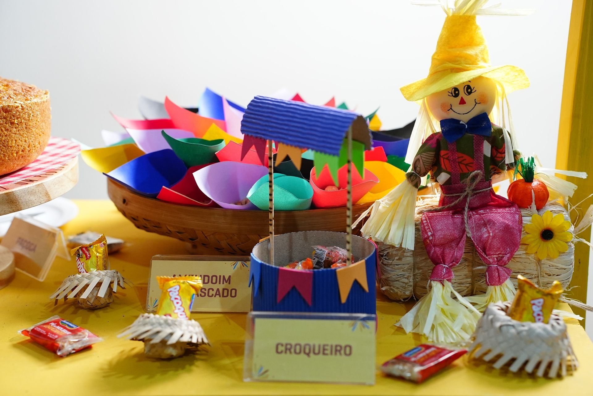 Decoração de festa junina com espantalho, doces típicos e enfeites coloridos.
