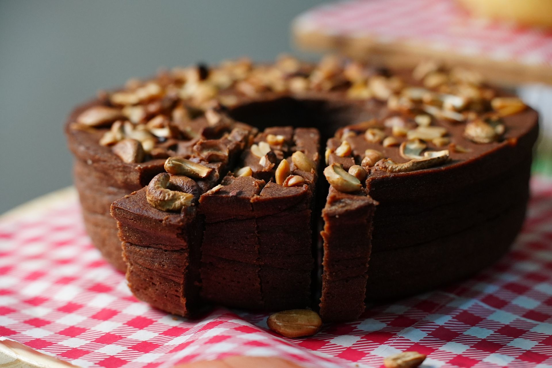 Bolo de pé de moleque coberto com castanhas sobre toalha xadrez.