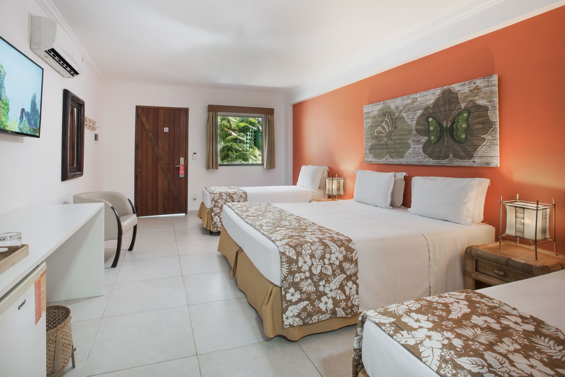 Apartamento econômico com três camas, ambiente confortável, ar-condicionado e vista para os jardins do resort.