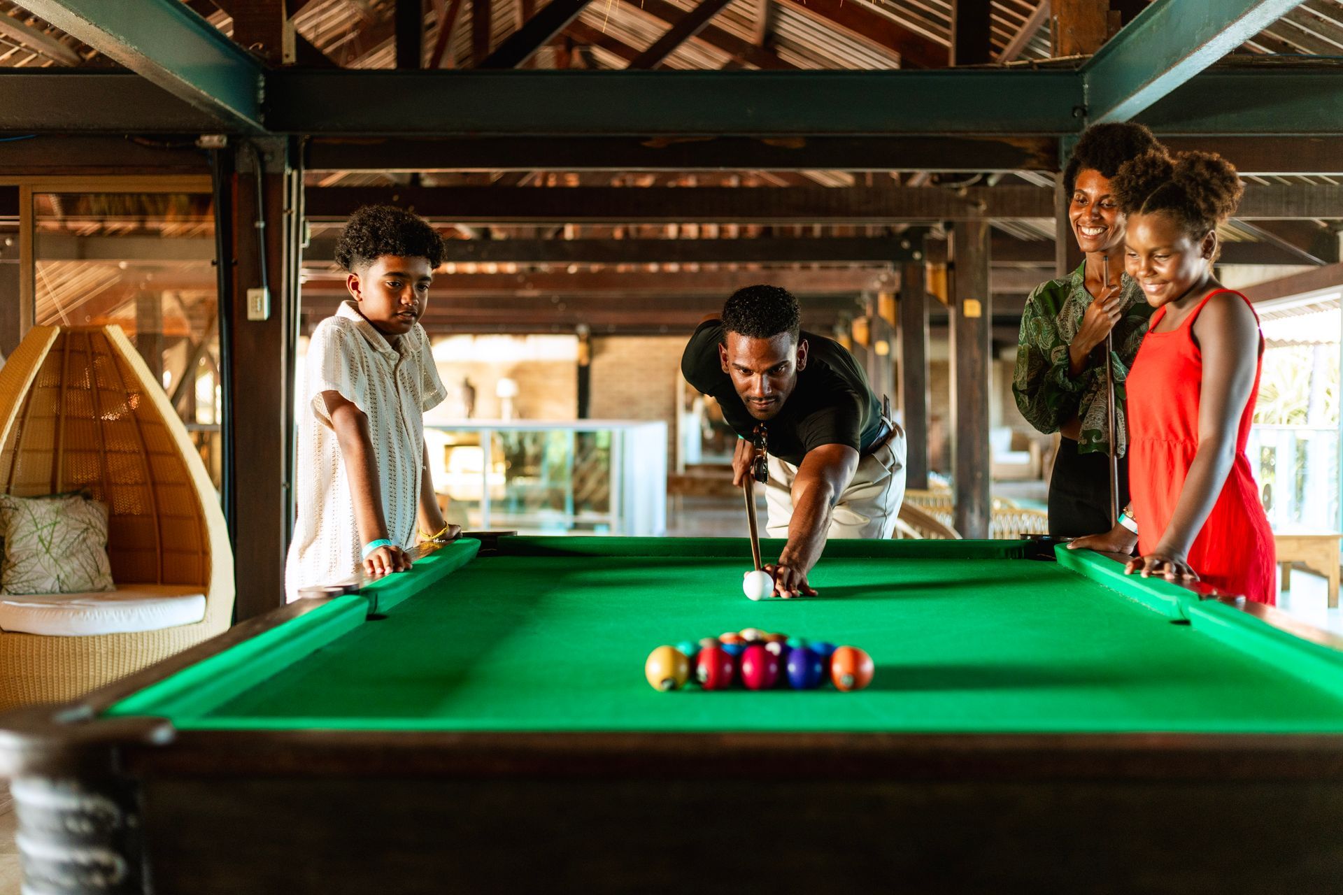 família se divertindo jogando sinuca em mezanino do resort.