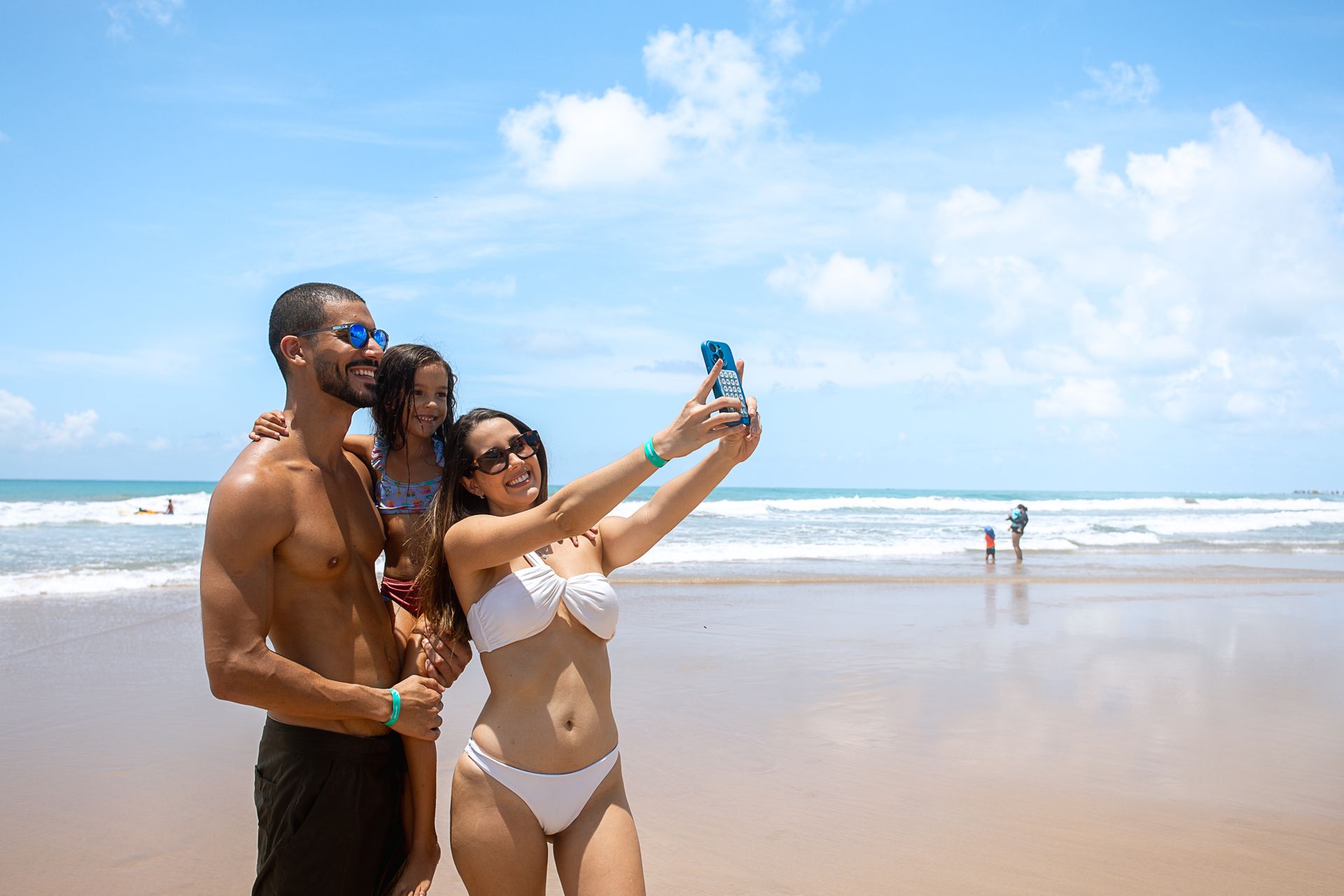 Família faz uma selfie à beira-mar durante um dia de praia, aproveitando momentos de lazer e diversão no Armação Resort.