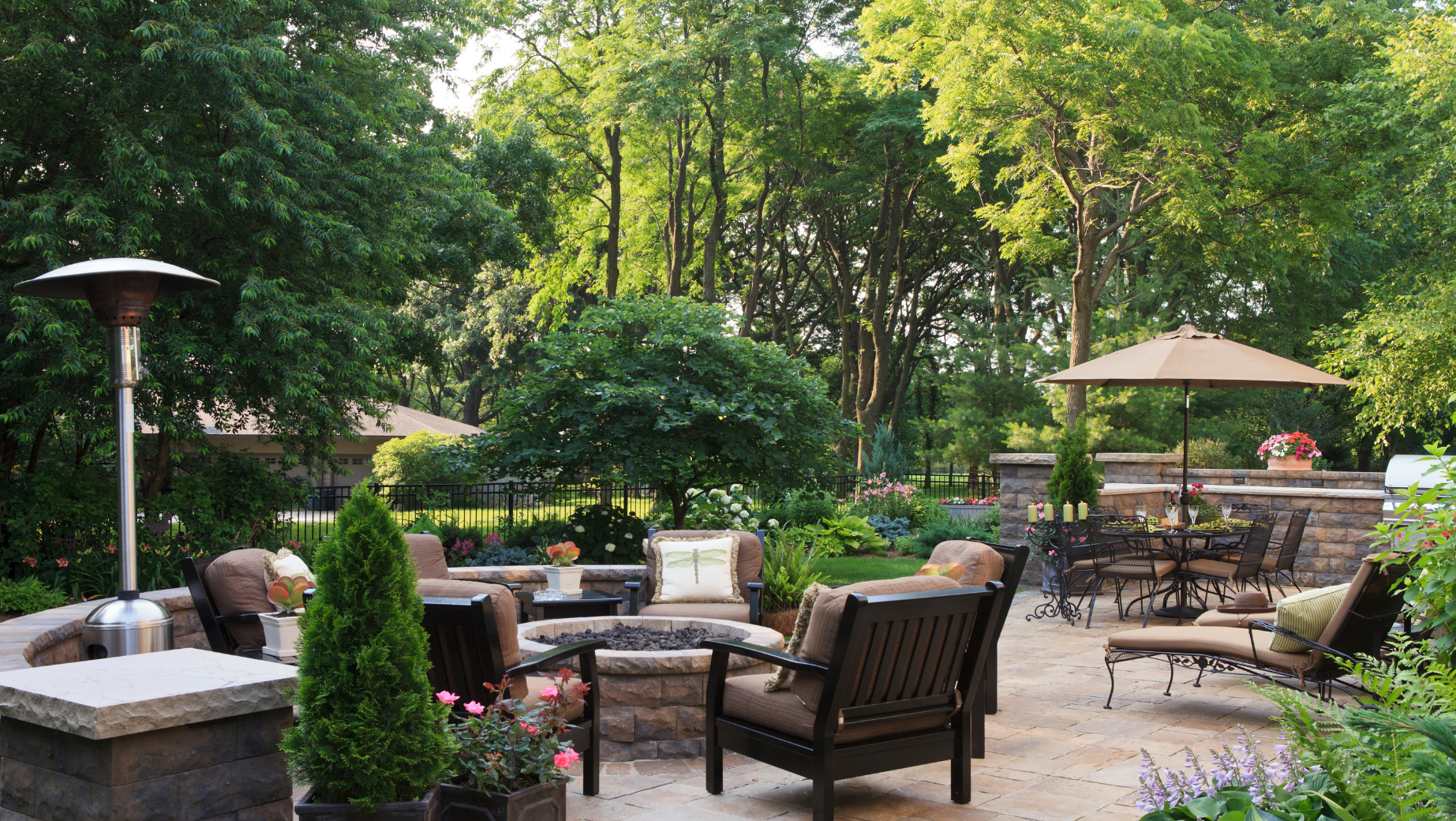 A patio with a lot of outdoor furniture, umbrellas, and professional landscaping in Vermont