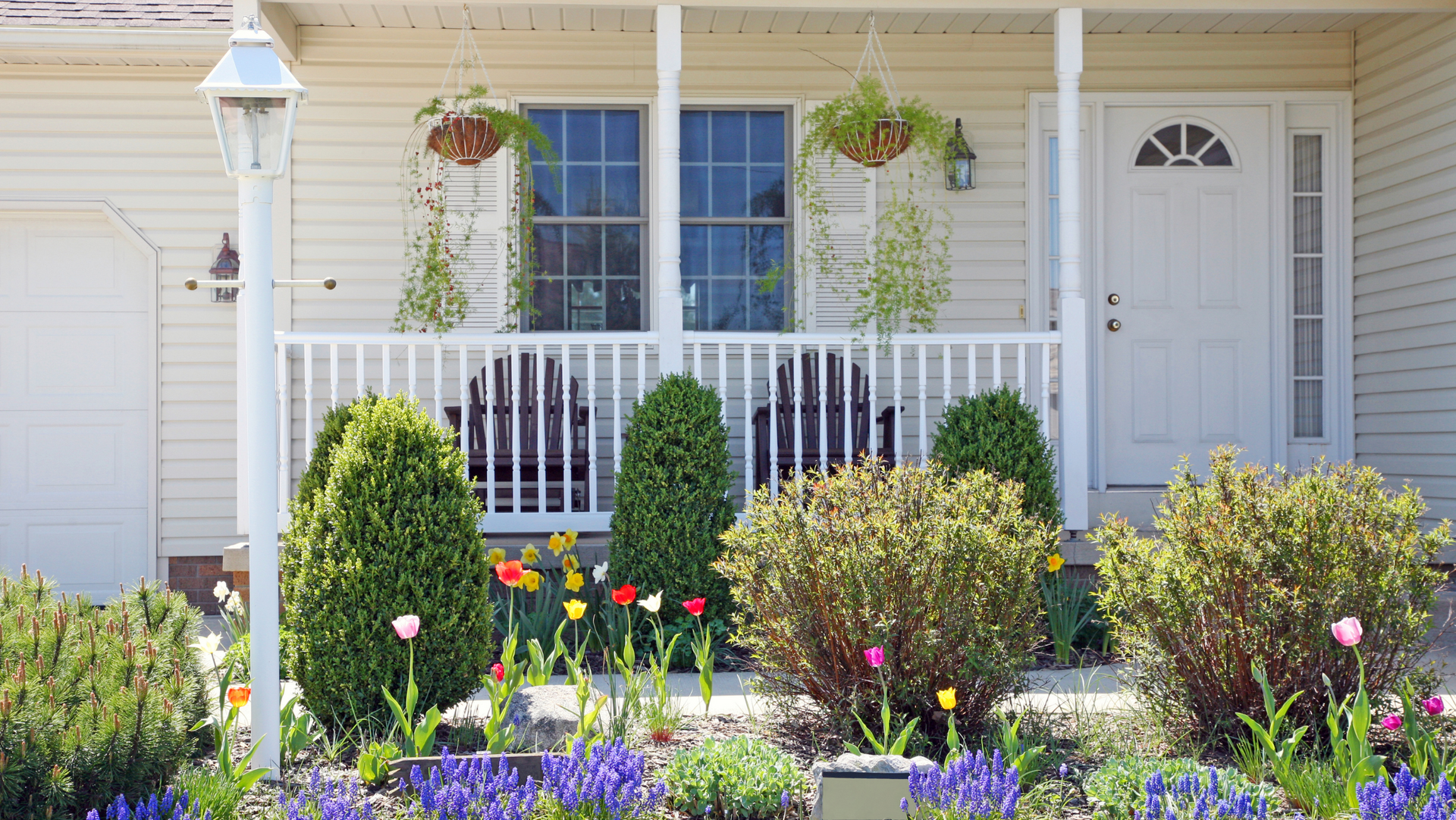 A white house in Vermont with a porch and flowers in front of it