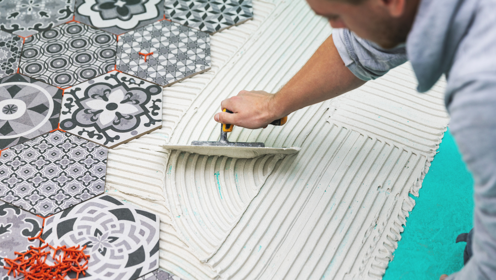 Contractor laying down grey and white patterned bathroom tiles on the floor