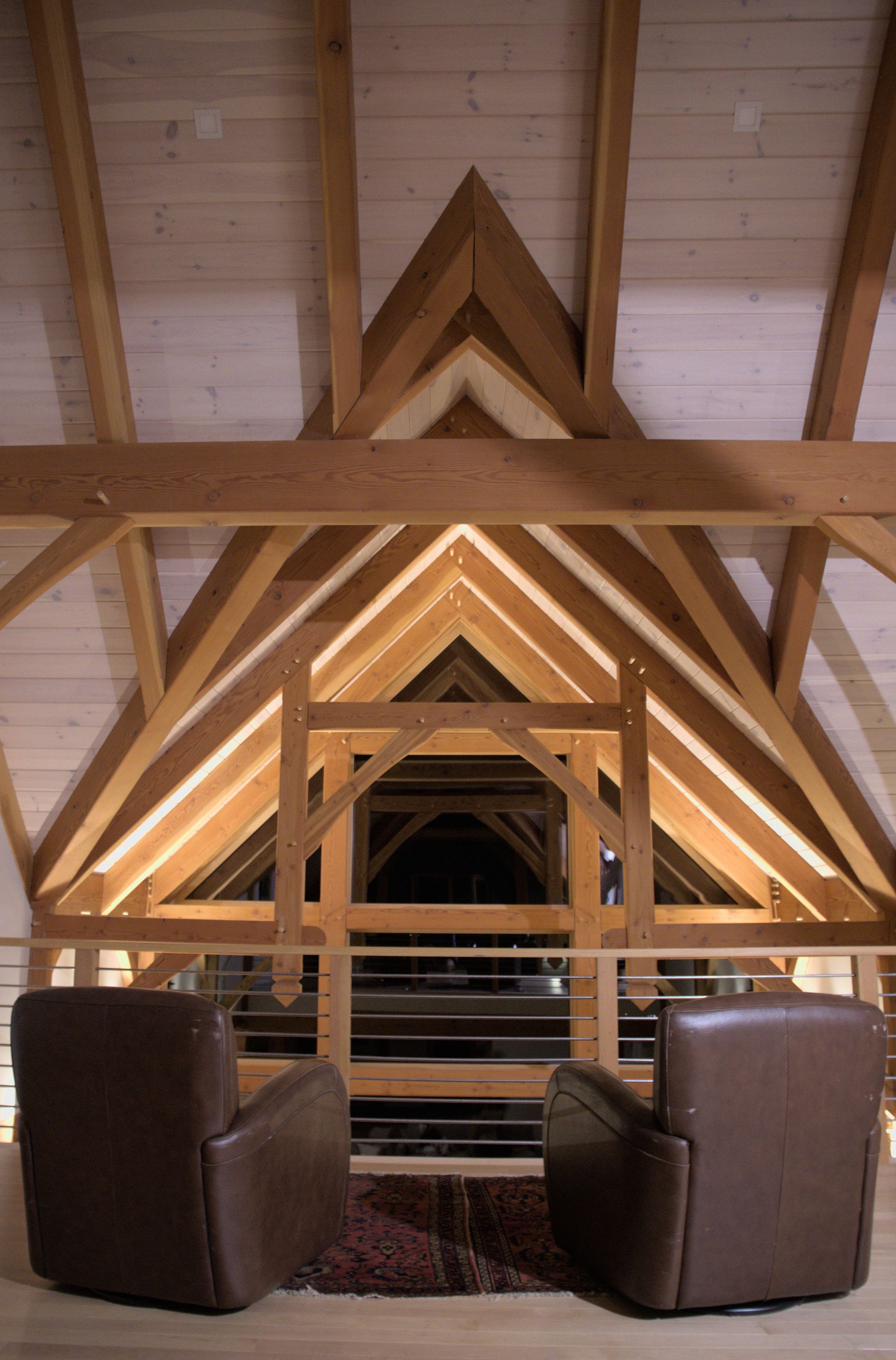 Cozy post-and-beam interior with exposed timber trusses and warm wood ceilings.