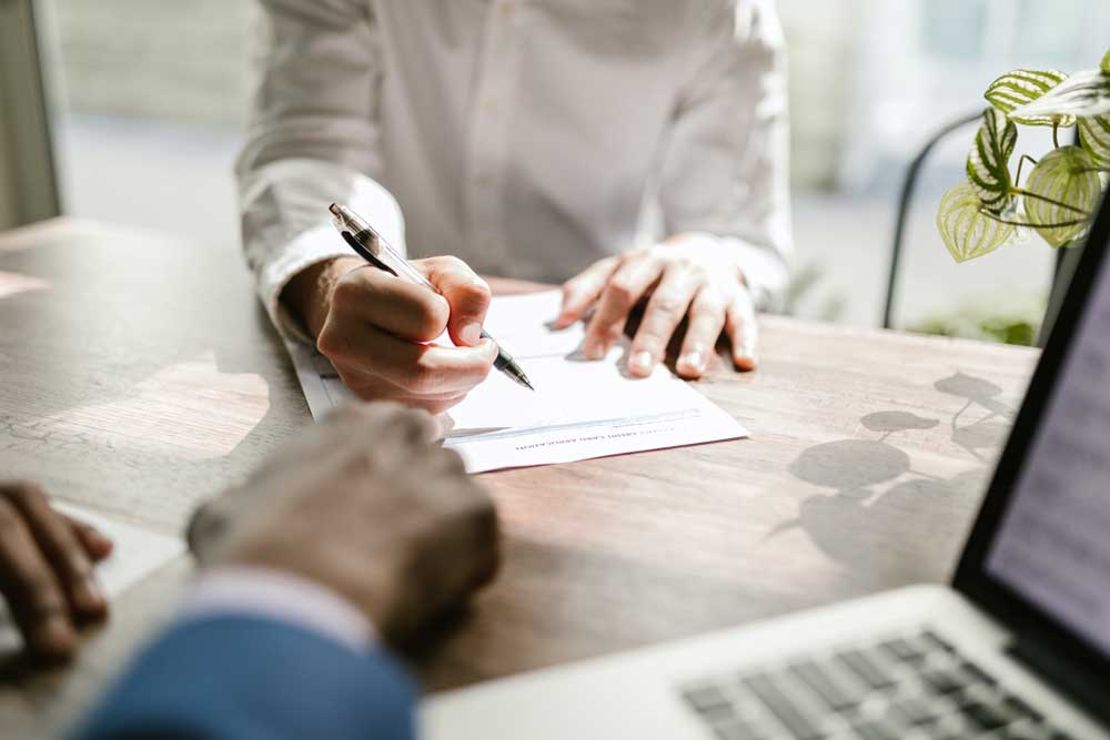 A man and a woman are sitting at a table writing on a piece of paper.