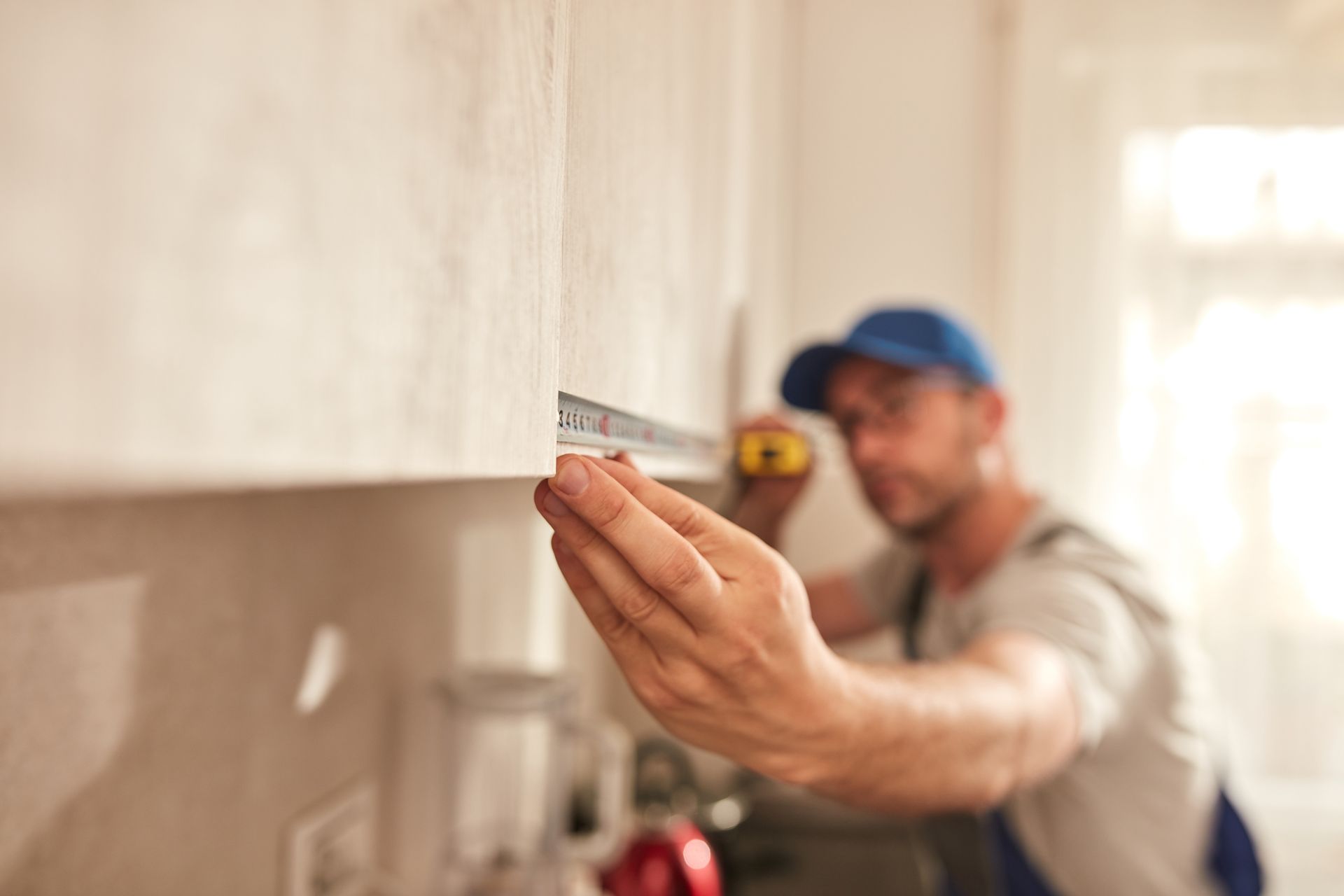Handyman fixing kitchen cabinets in the apartment.