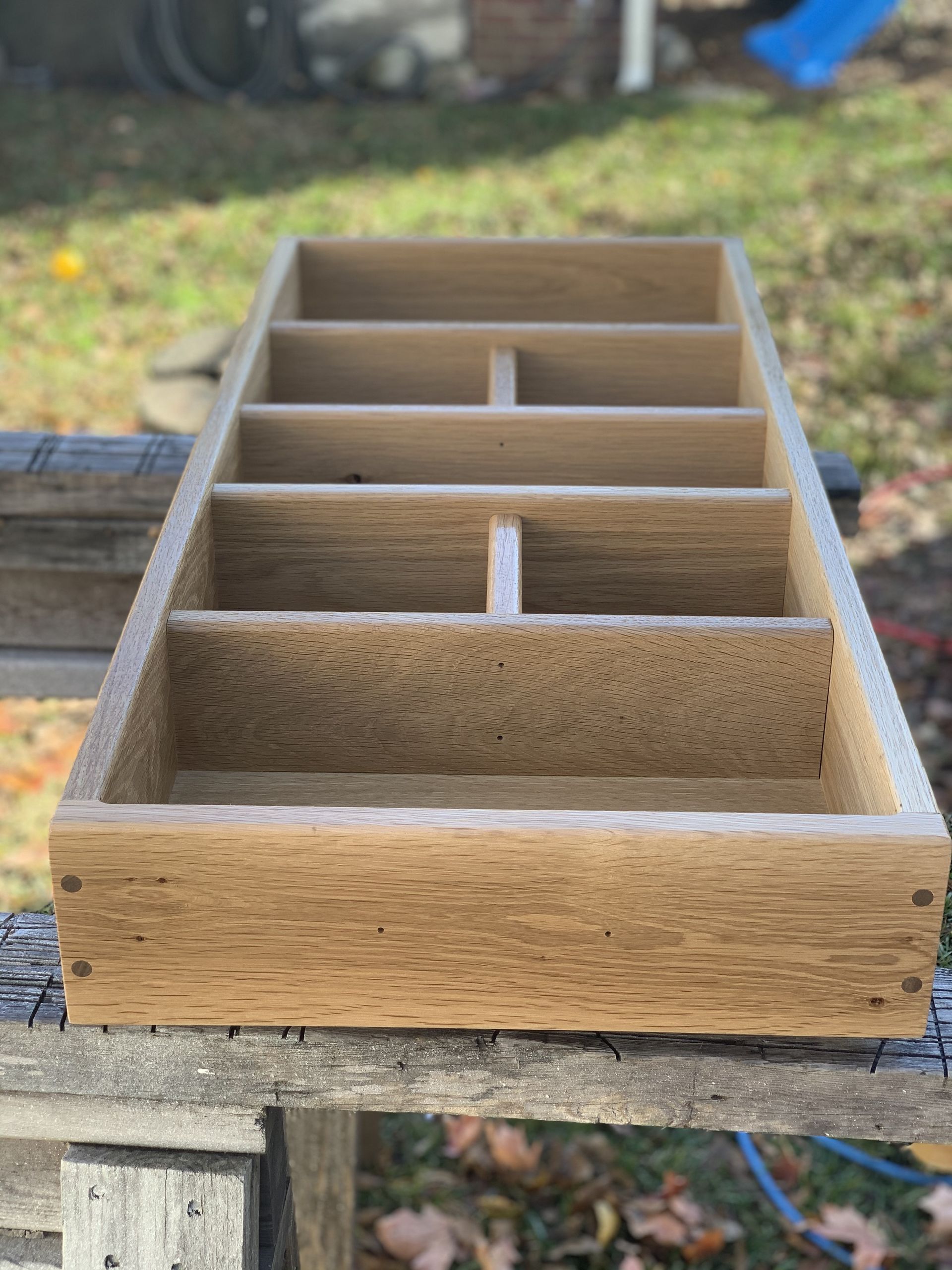 Wooden compartment organizer box with six divided sections on a weathered outdoor table.