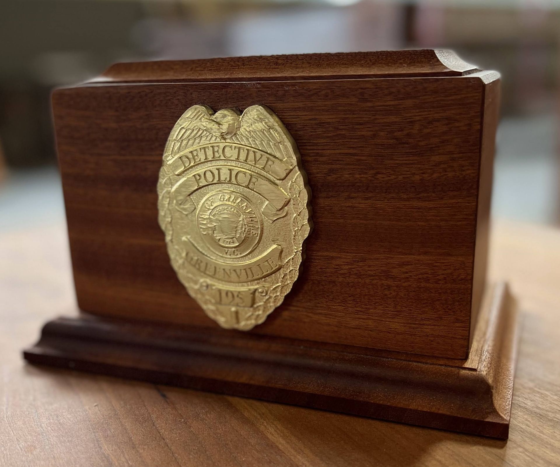 Wooden plaque with a gold police badge emblem on a stand