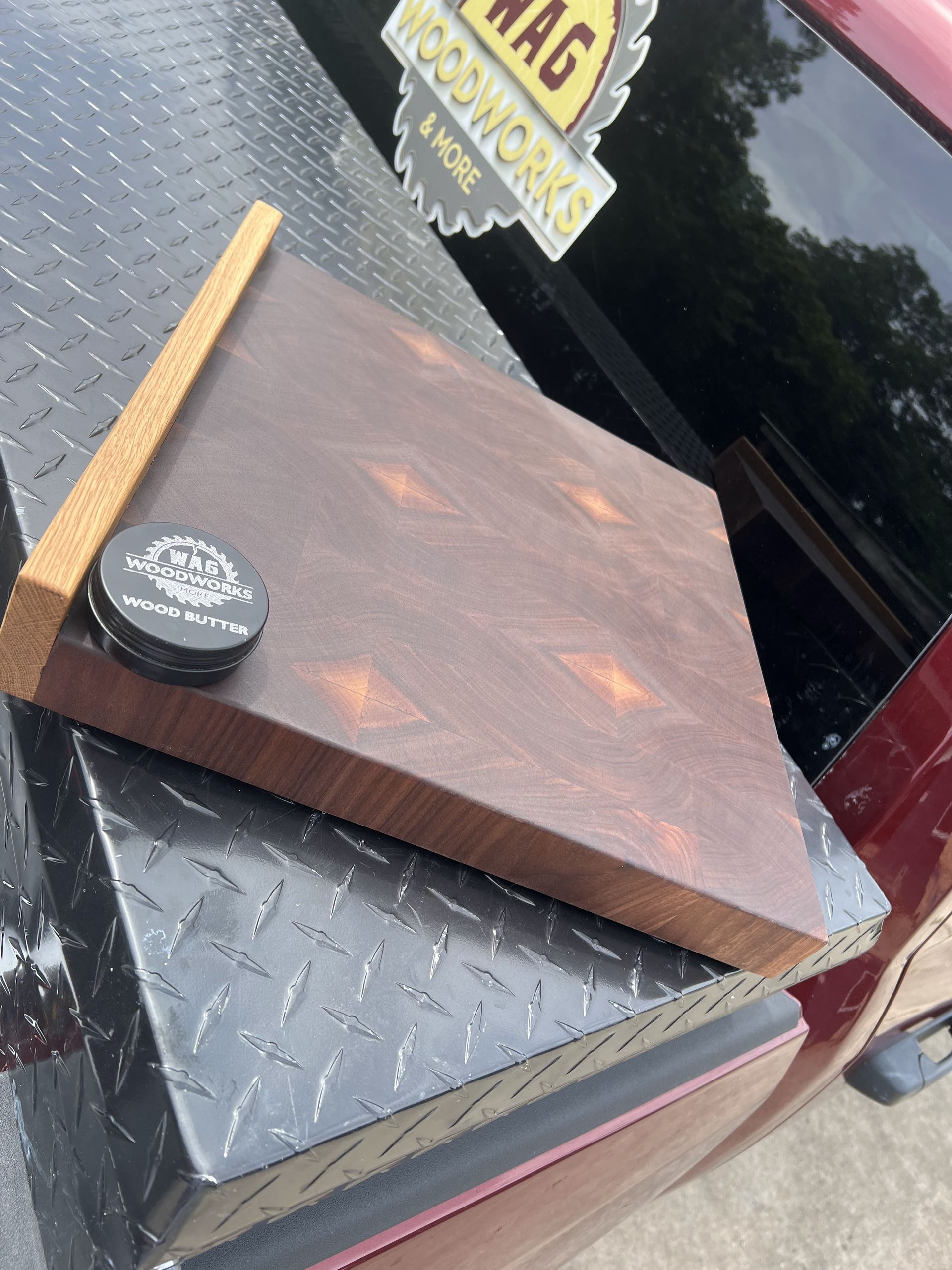 Wooden board on a metal truck bed next to a small round black cap, outdoors
