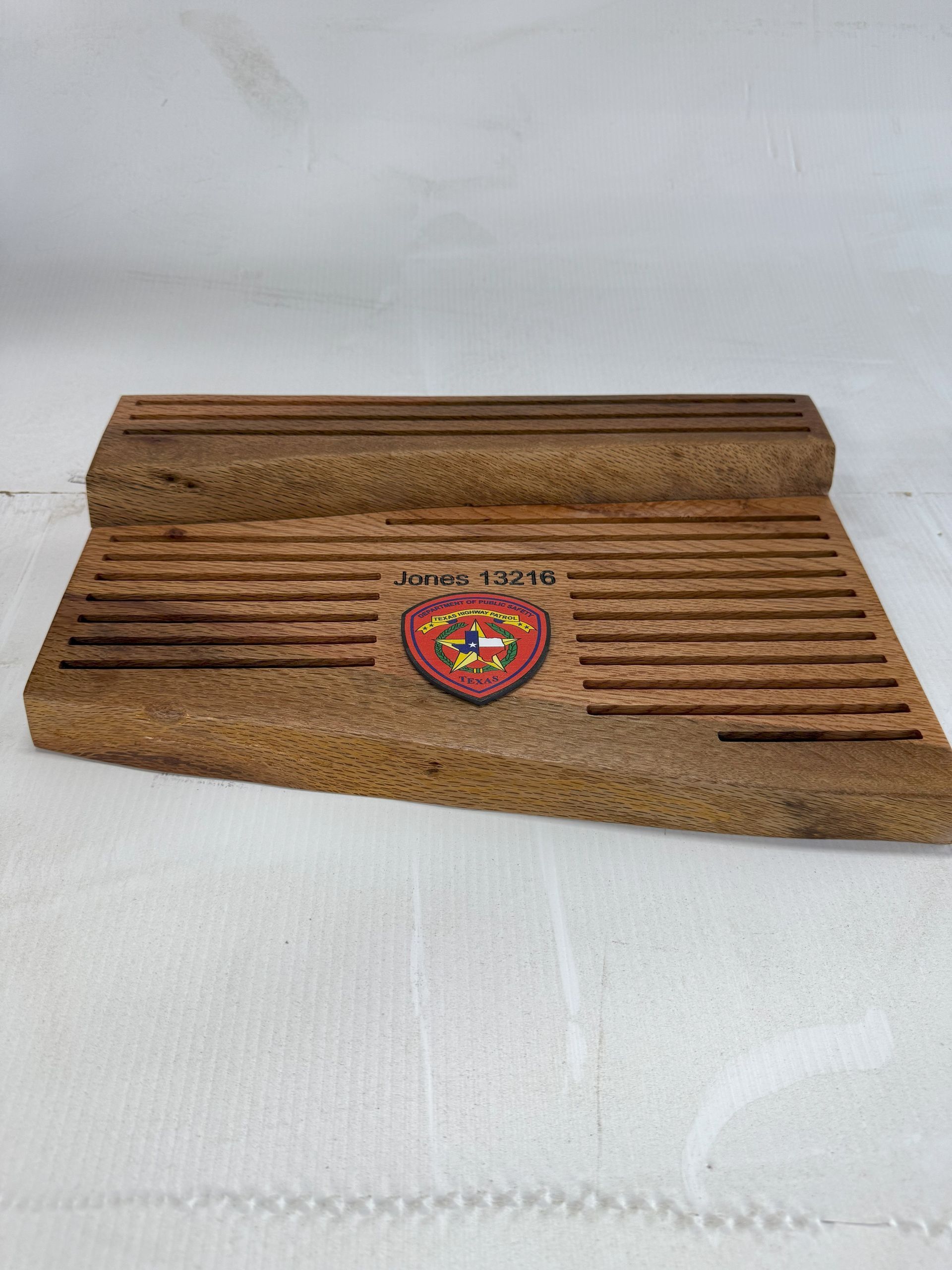 Wooden incense holder with grooved top and a colorful central emblem on a white surface