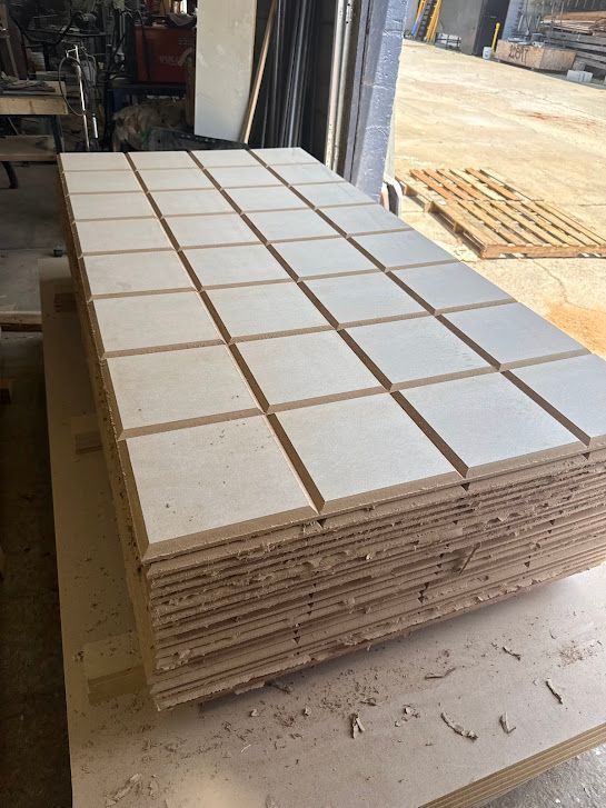 Stack of beige square tiles on a pallet in a workshop doorway