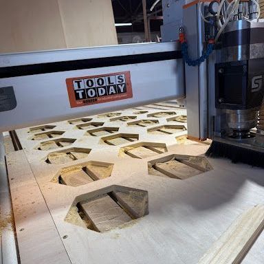 CNC router cutting hexagonal wood pieces on a workshop table, with sawdust and a Tools Today logo.