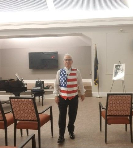 A man in an american flag shirt is walking in a room with chairs