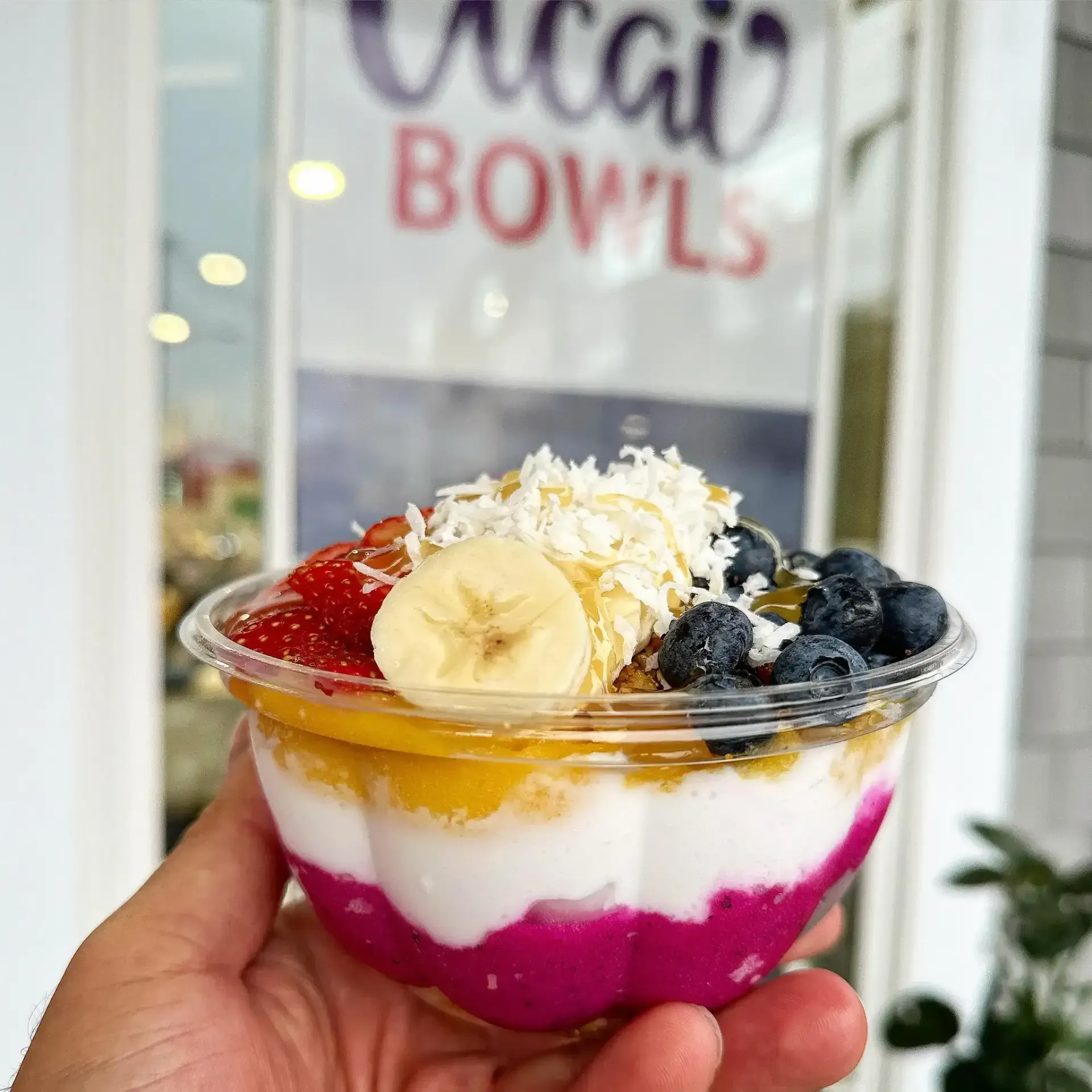 Colorful acai bowl topped with strawberries, banana slices, blueberries, coconut flakes, and granola