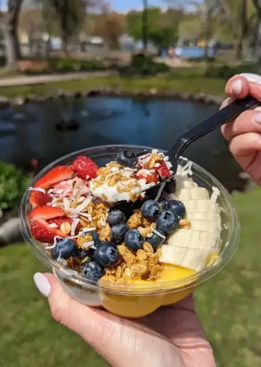 Colorful acai bowl topped with strawberries, banana slices, blueberries, coconut flakes, and granola