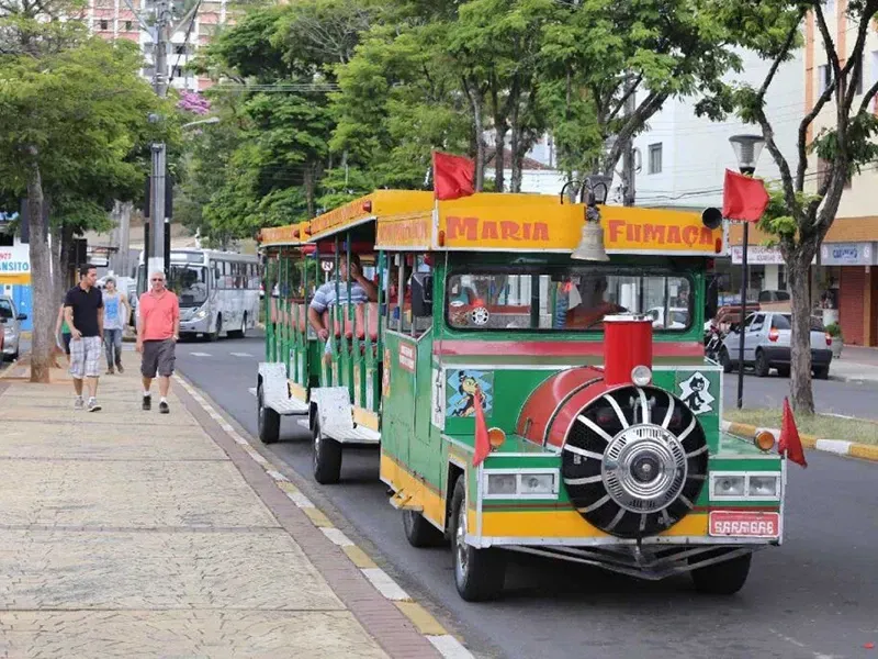 Um veículo turístico colorido com temática ferroviária, identificado como