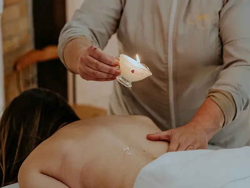 Durante um tratamento de spa, um massagista derrama óleo morno de uma pequena vela acesa nas costas de um cliente.