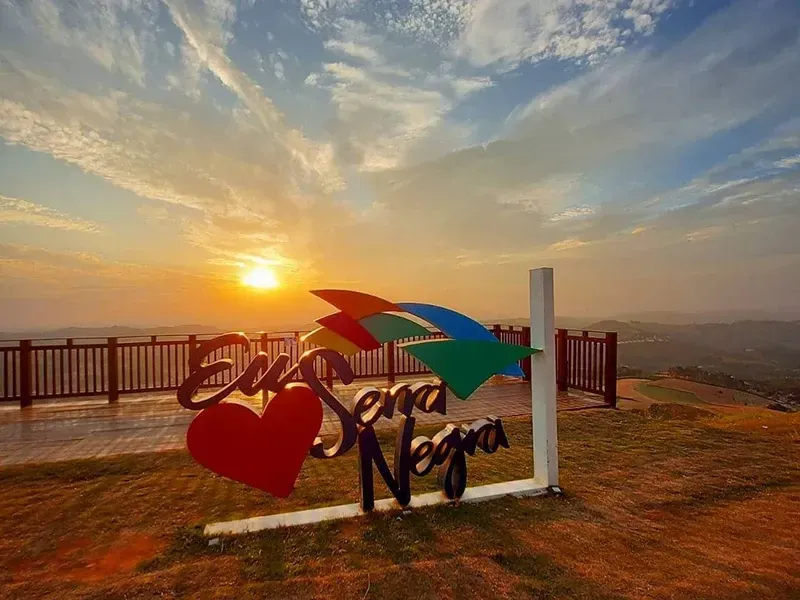 Um mirante panorâmico ao pôr do sol com uma placa que diz