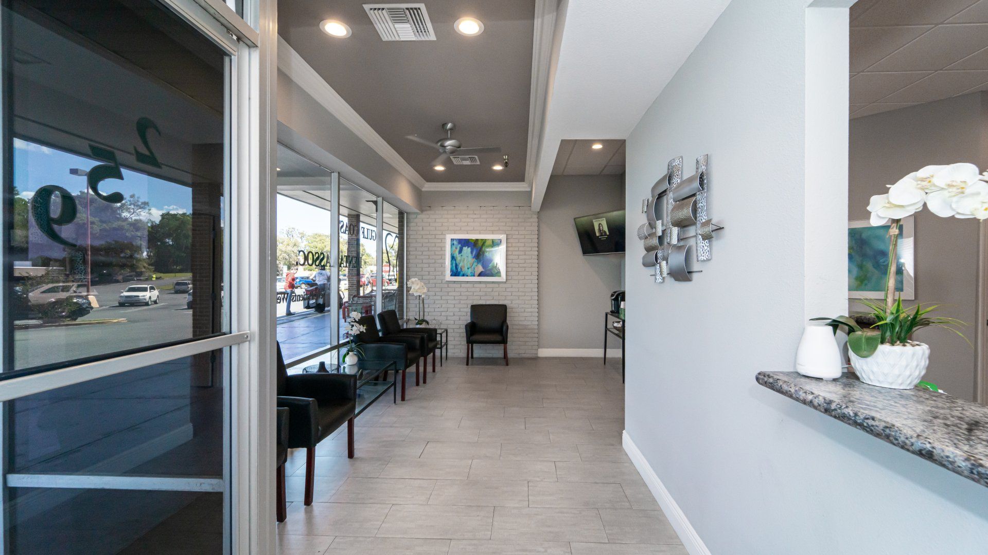 A long hallway in a dental office with chairs and a counter.