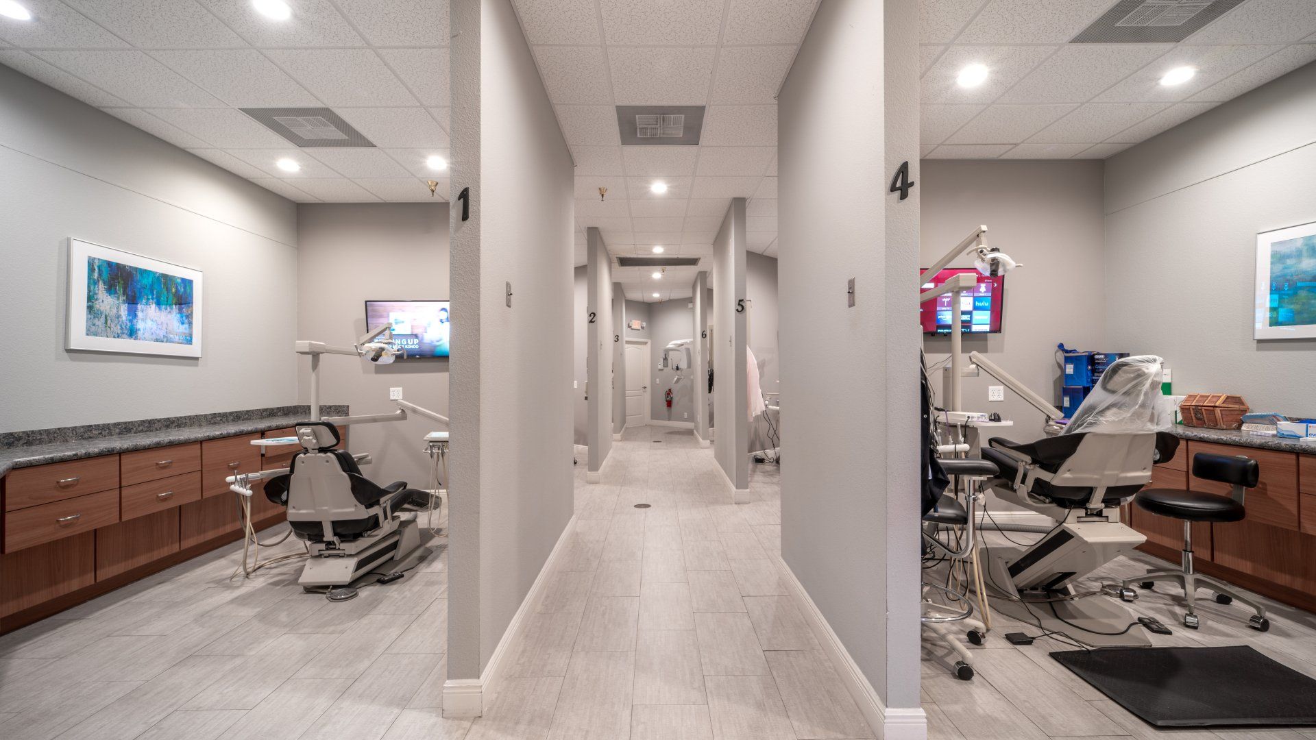 A long hallway in a dental office with a row of dental chairs.