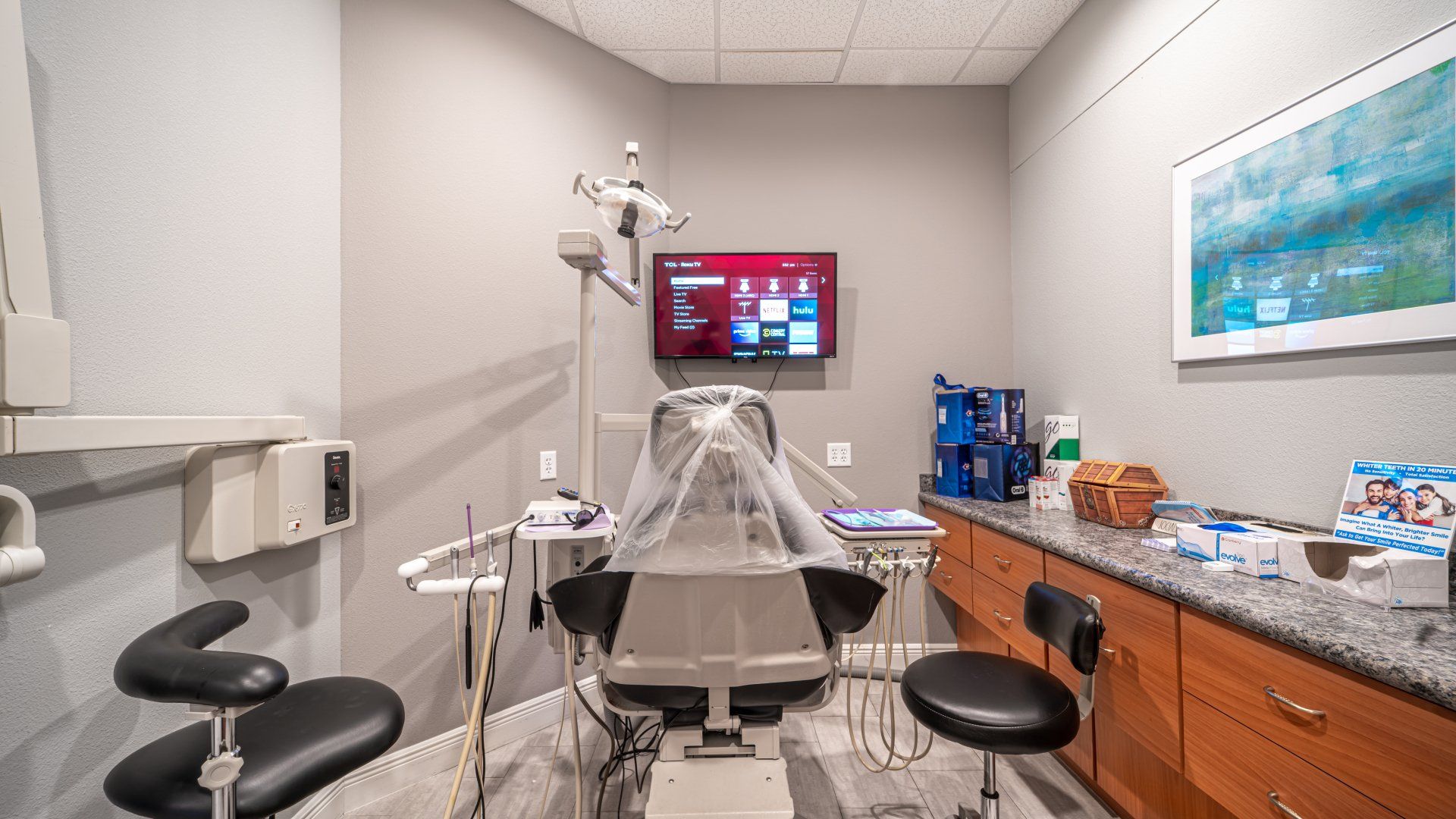 A dental office with a dental chair and a television on the wall.