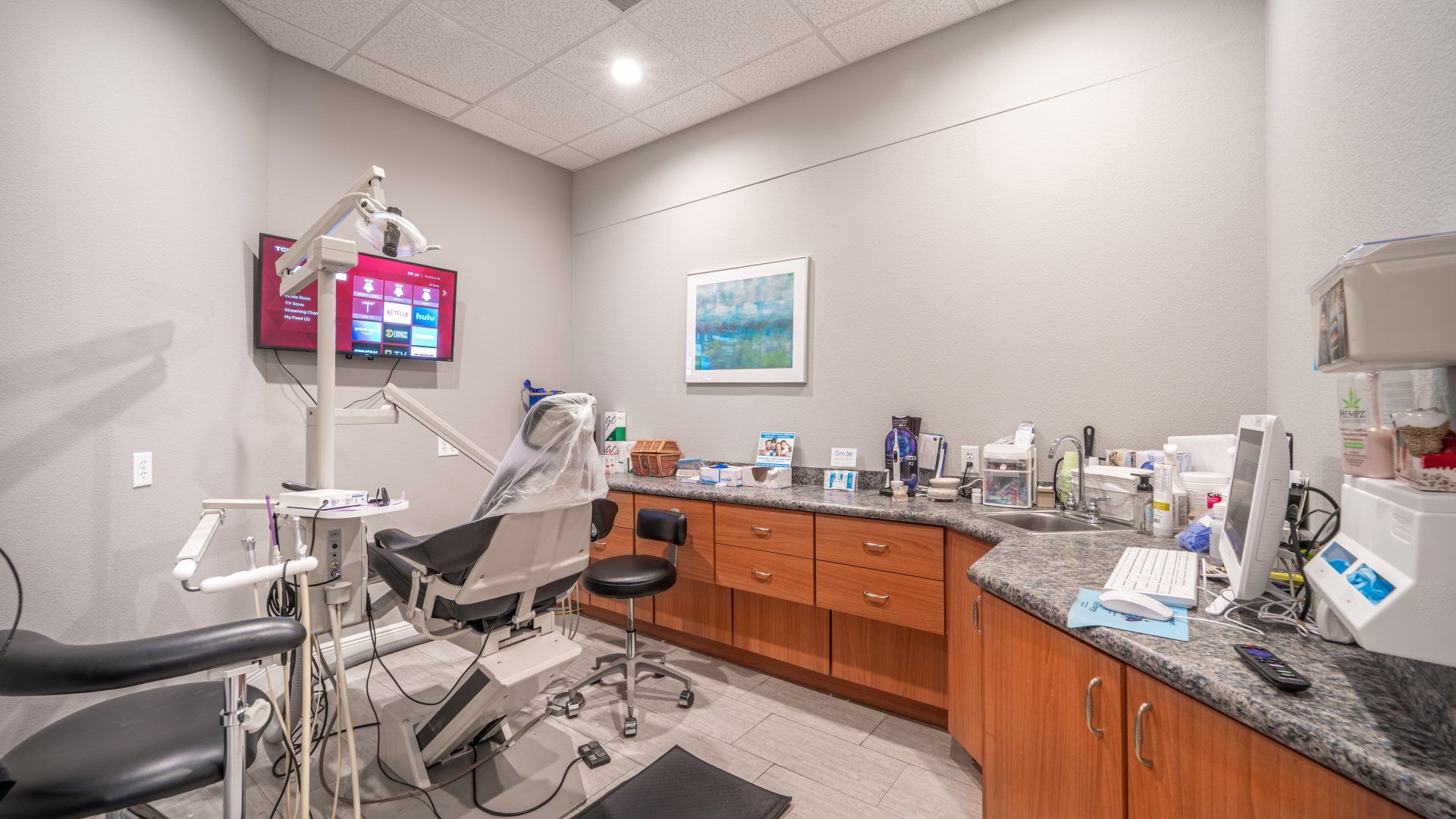 A dental office with a dental chair and a television on the wall.