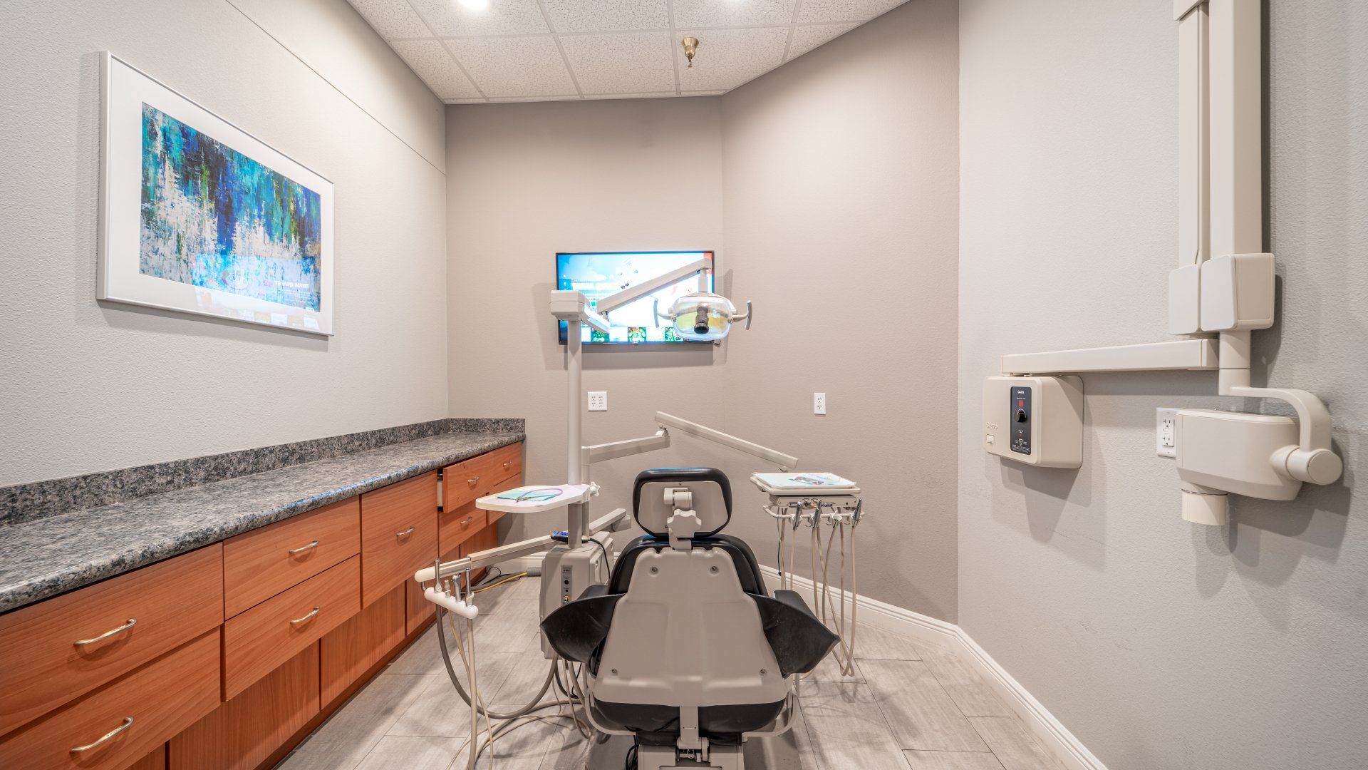 A dental office with a dental chair and a television on the wall.