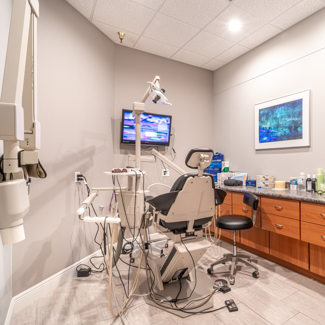 A dental office with a dental chair and a television on the wall.