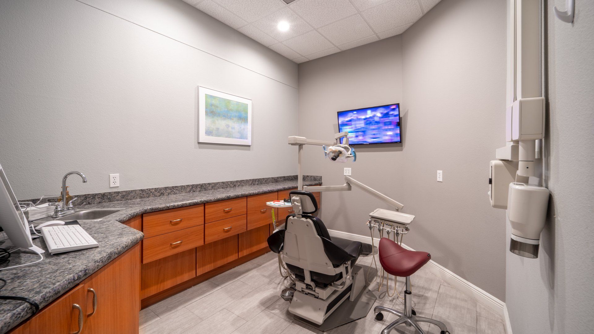 A dental office with a dental chair and a television on the wall.