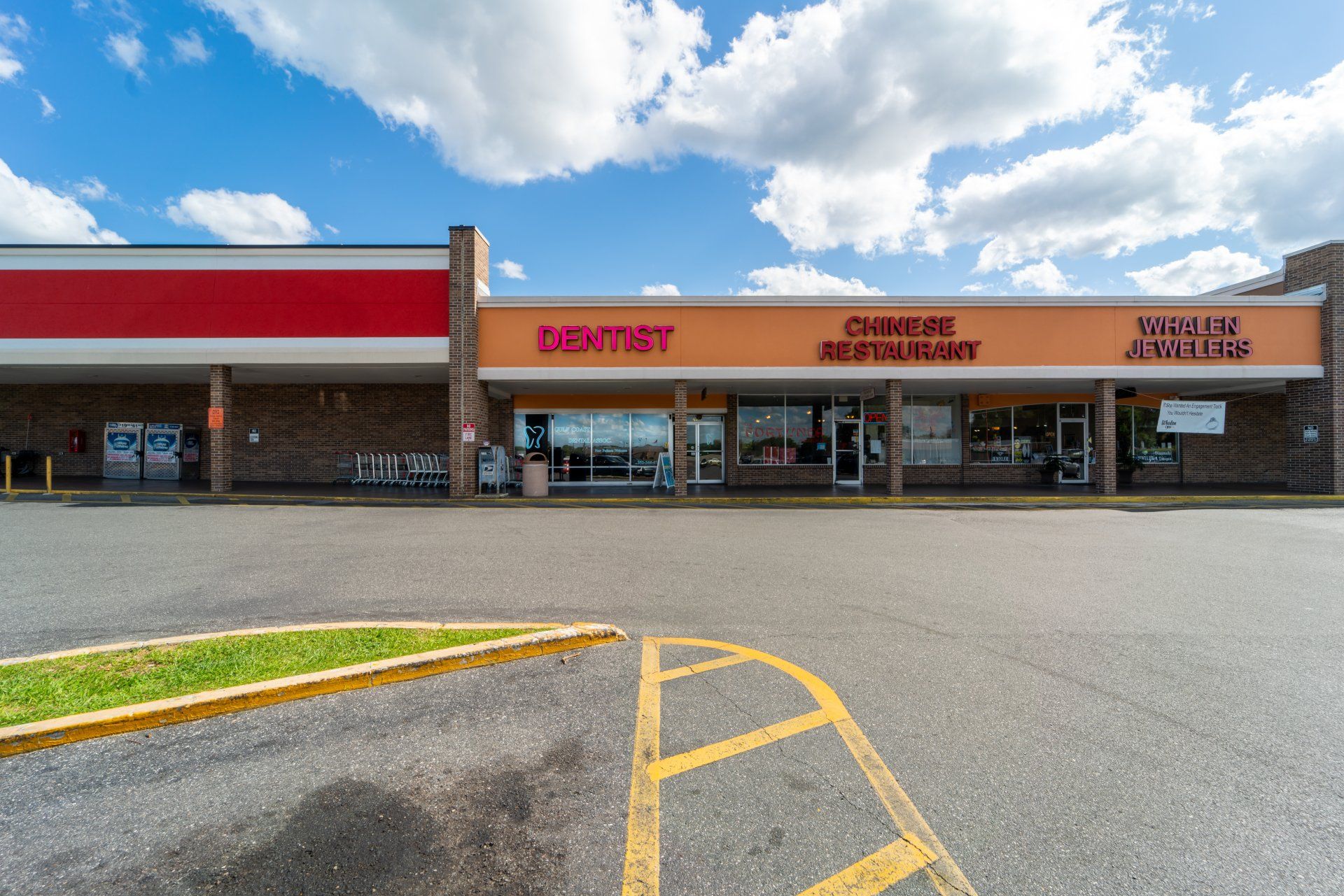 A dentist 's office is located in a shopping center next to a parking lot.