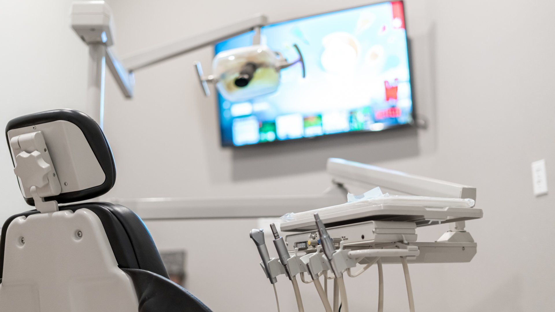 A dental office with a dental chair and a television on the wall.