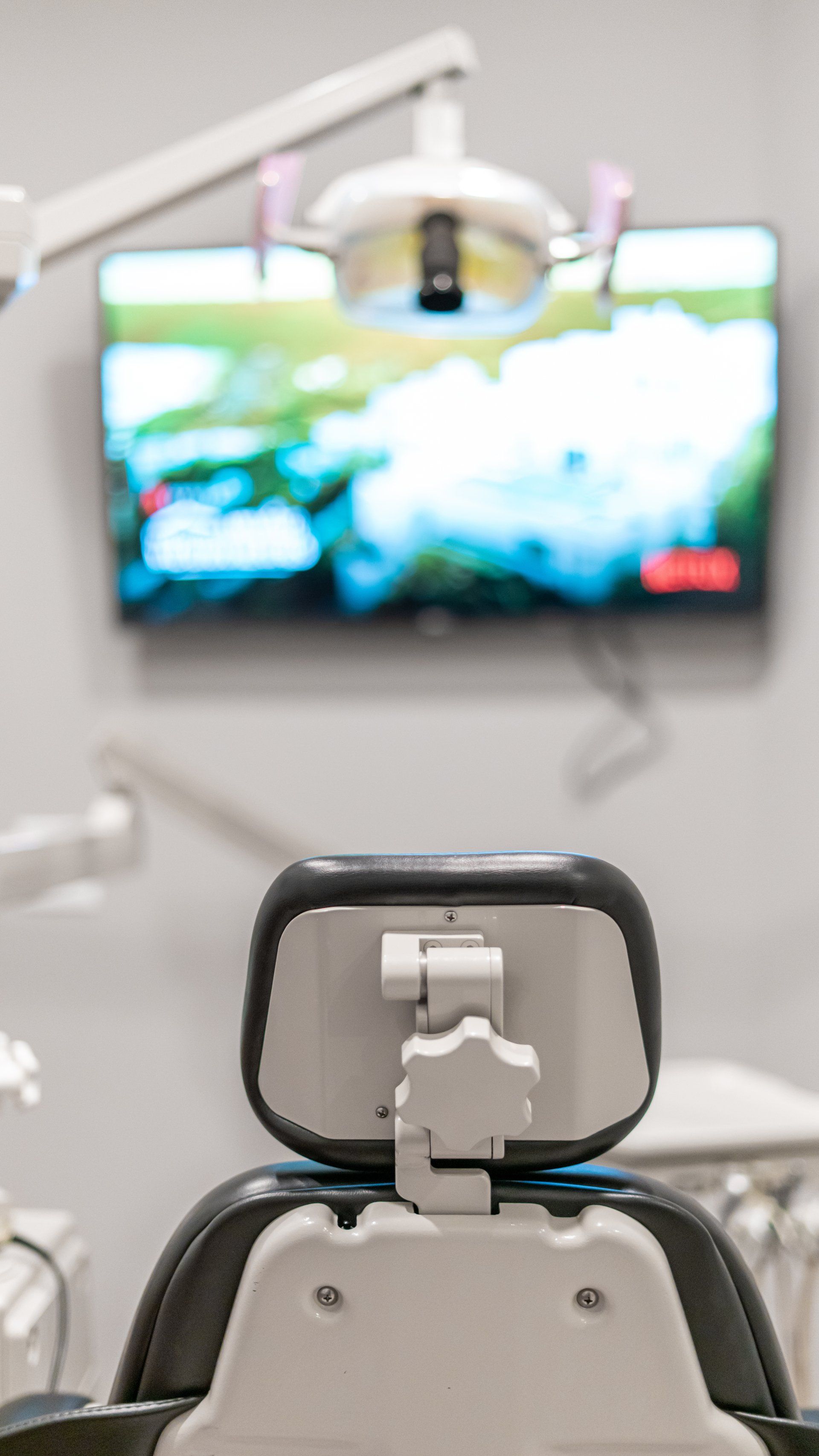 A dental chair is sitting in front of a television in a dental office.