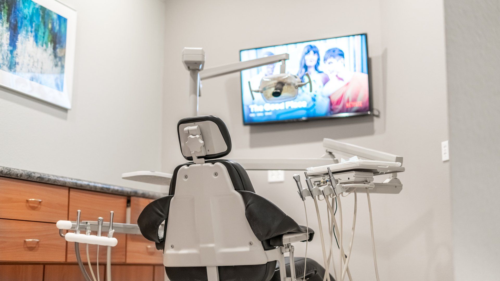 A dental office with a dental chair and a television on the wall.