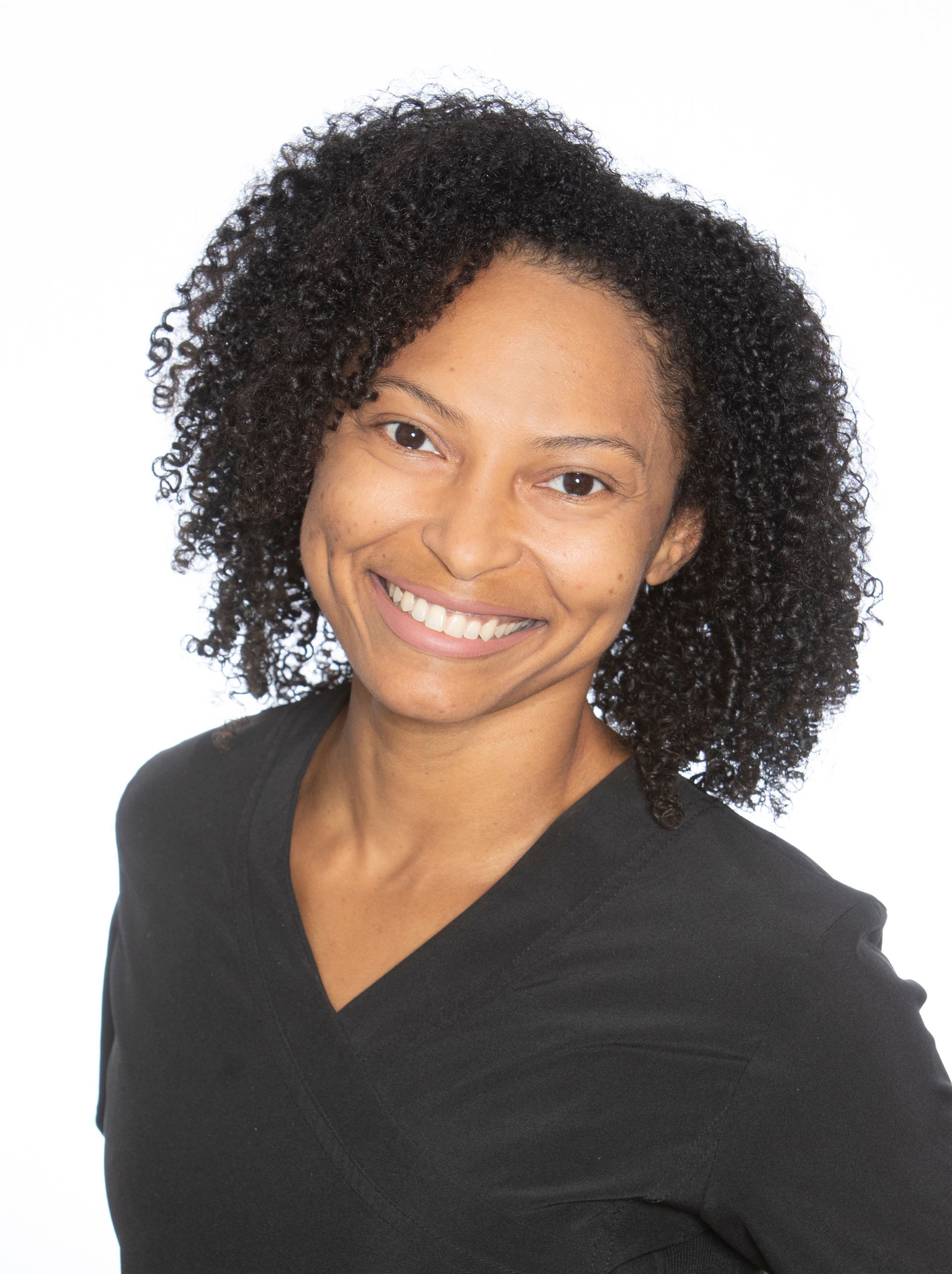 A woman with curly hair is smiling and wearing a black shirt