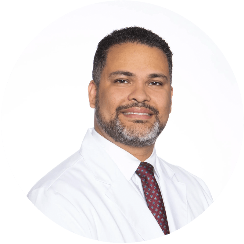 A man with a beard is wearing a white coat and tie.