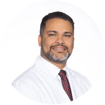 A man with a beard is wearing a white coat and tie.