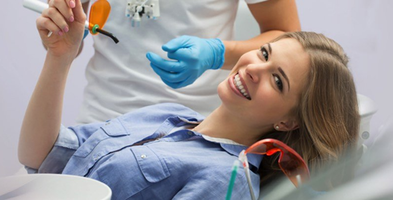 A woman is smiling while sitting in a dental chair.