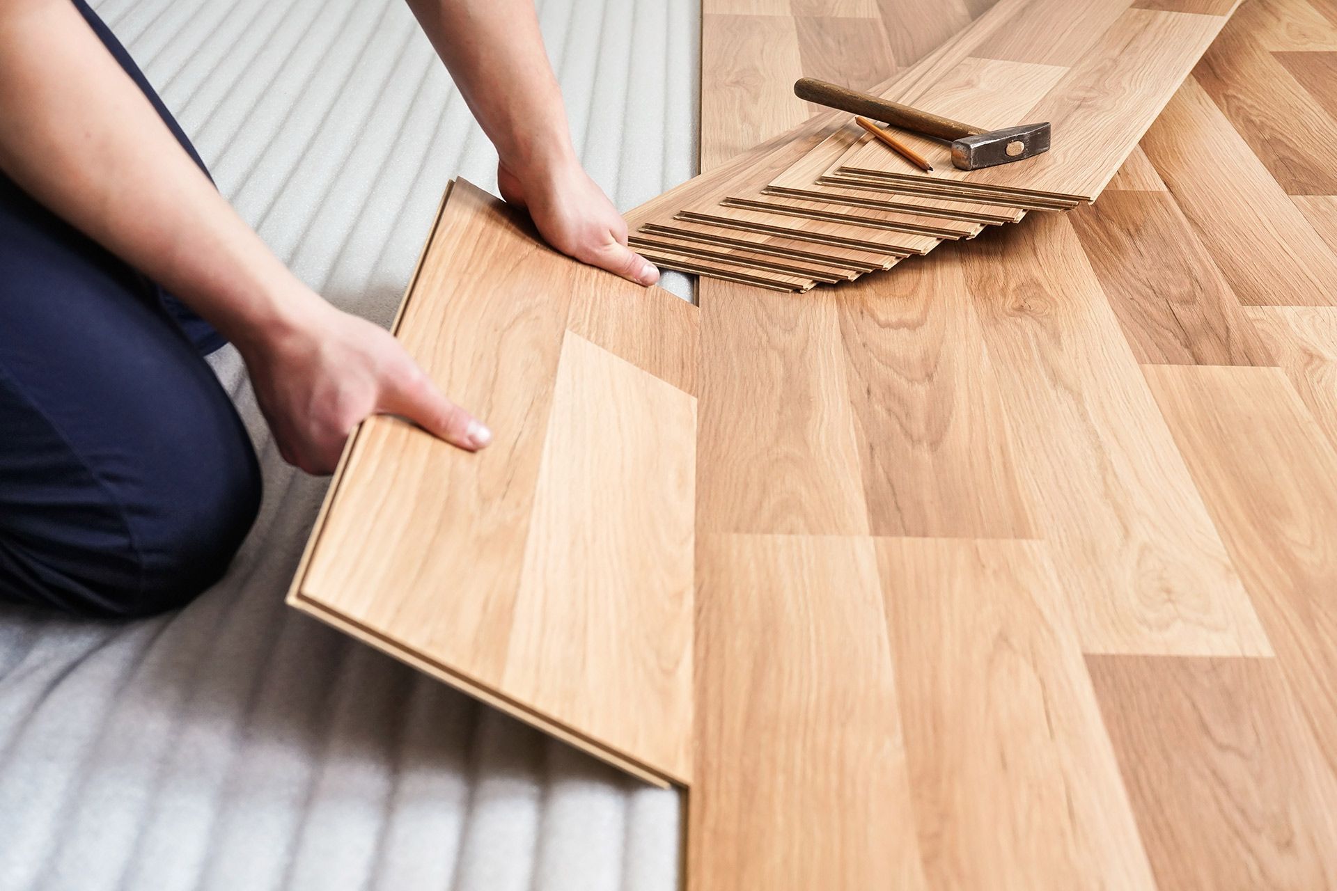 Installing wood flooring with planks and a flooring tool in a room