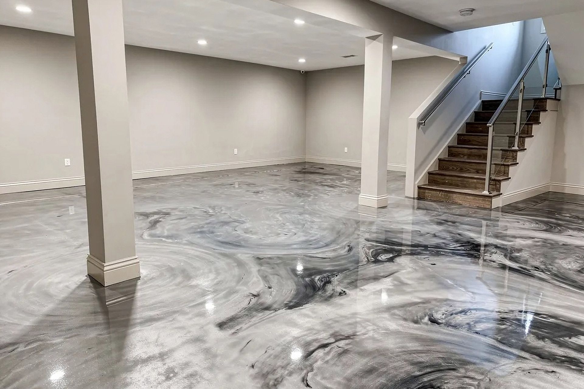 Empty basement with glossy gray marbled floor and stairs leading upstairs