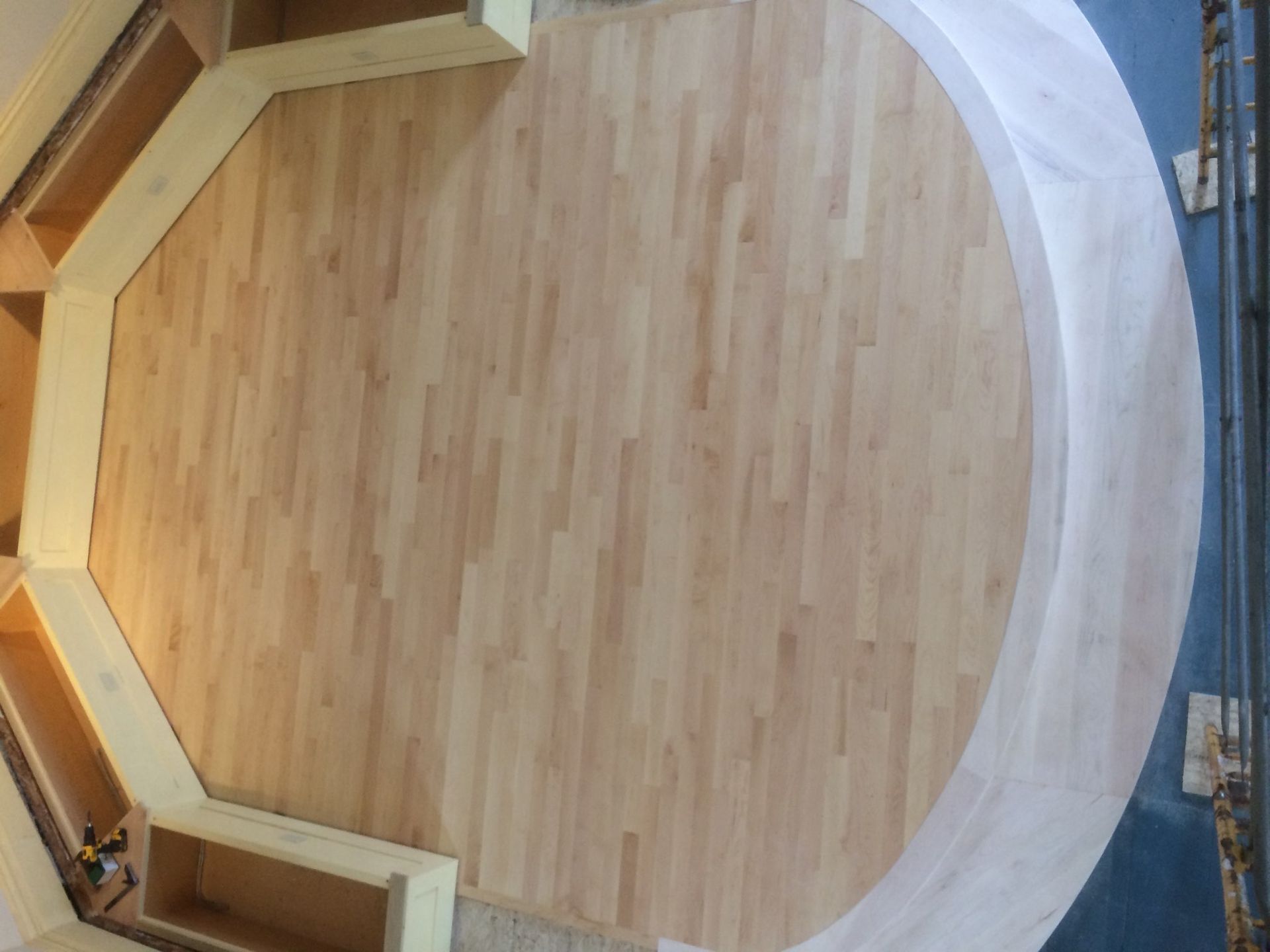 Wooden indoor racetrack with a curved white barrier and hexagonal corners from above