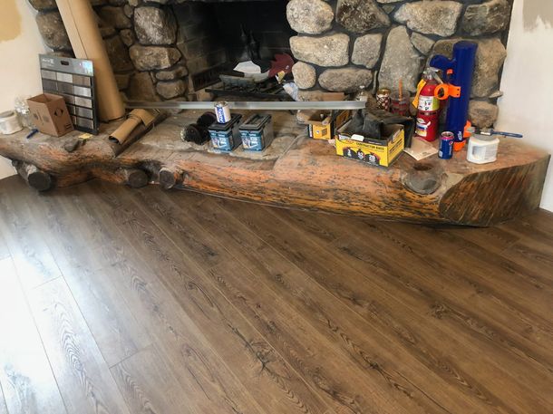 Living room hearth with toys and figurines on a stone fireplace ledge, above a wooden floor.