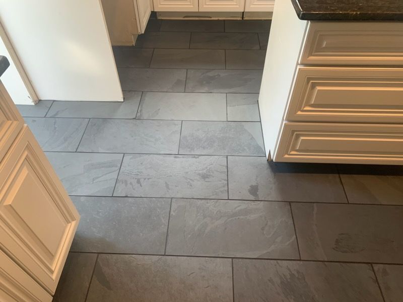 Kitchen doorway with gray tiled floor and white cabinets on both sides