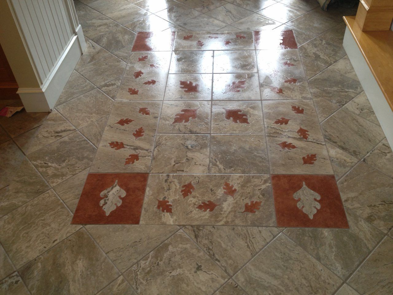 Decorative tiled hallway floor with red leaf-patterned inlays and a glossy finish