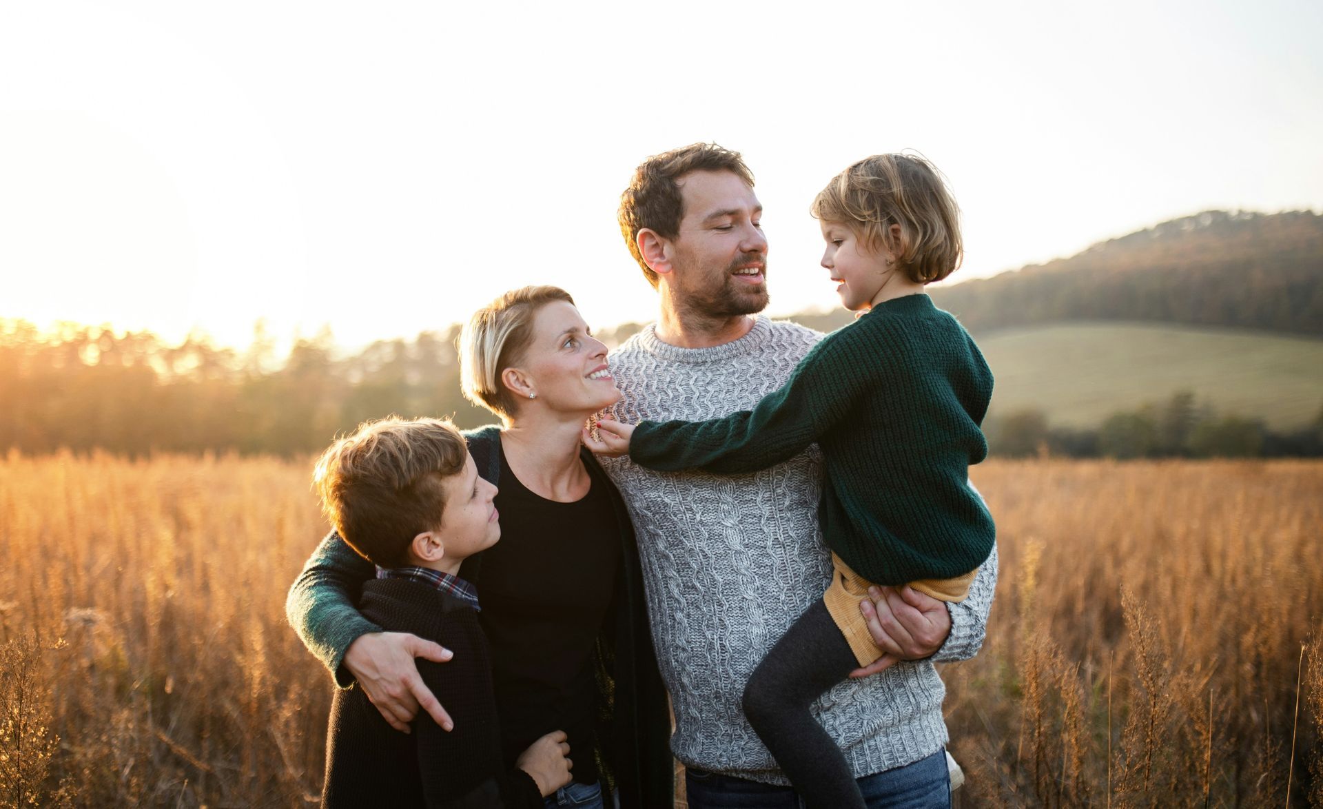 A family is posing for a picture in a field at sunset.