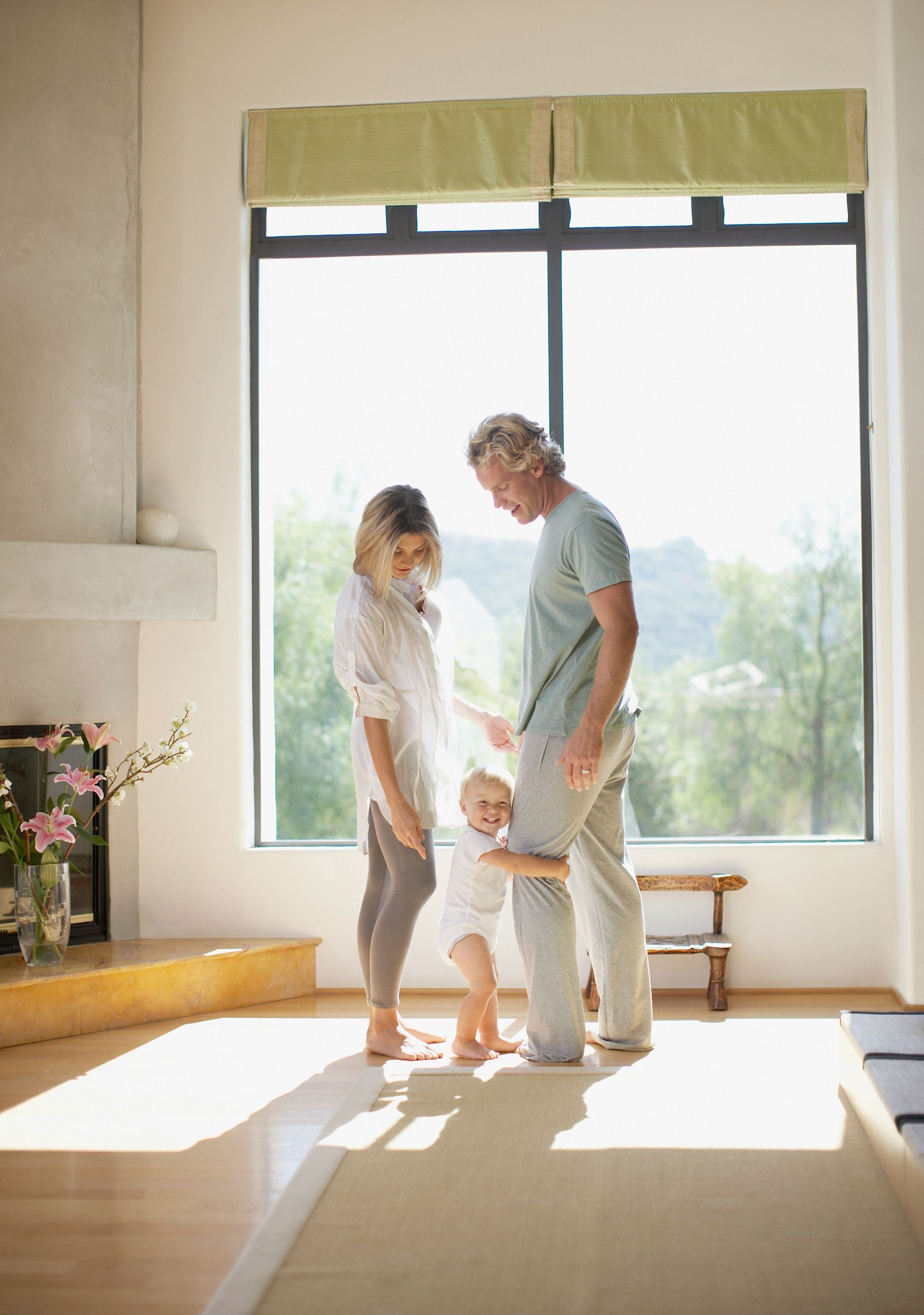 A family is standing in a living room holding a baby.