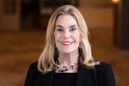 A woman in a black jacket and white shirt is smiling for the camera.