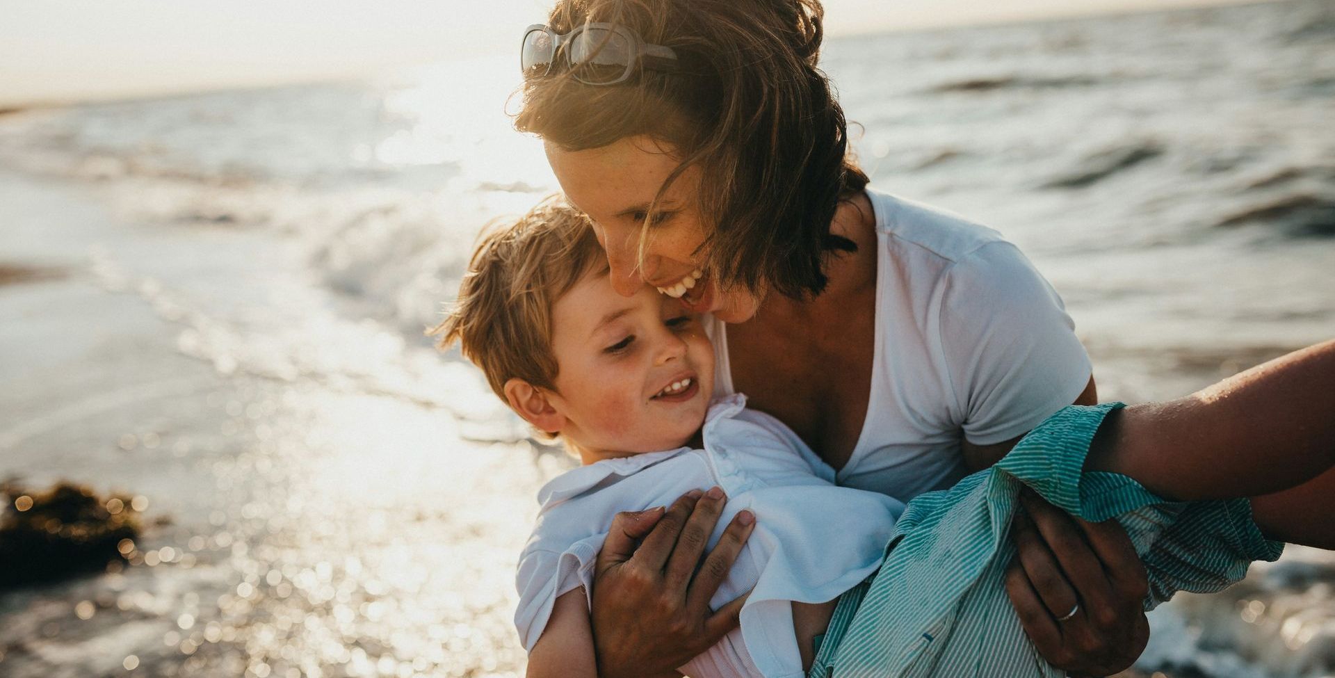 A woman is holding a little boy on the beach.