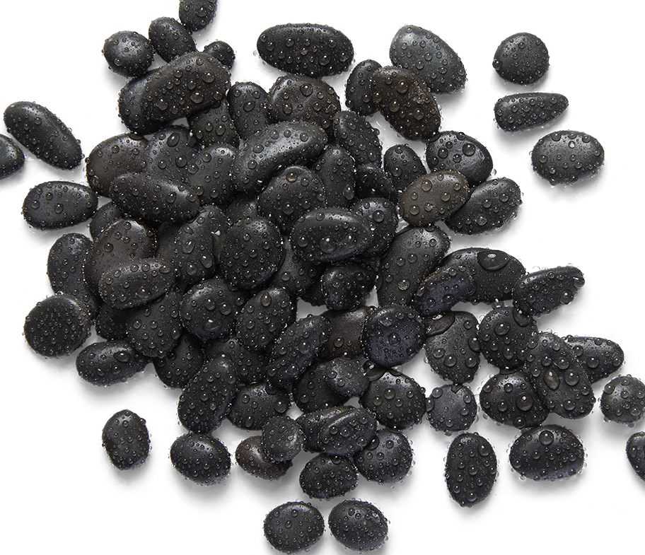 Black, wet, smooth stones scattered on a white surface.