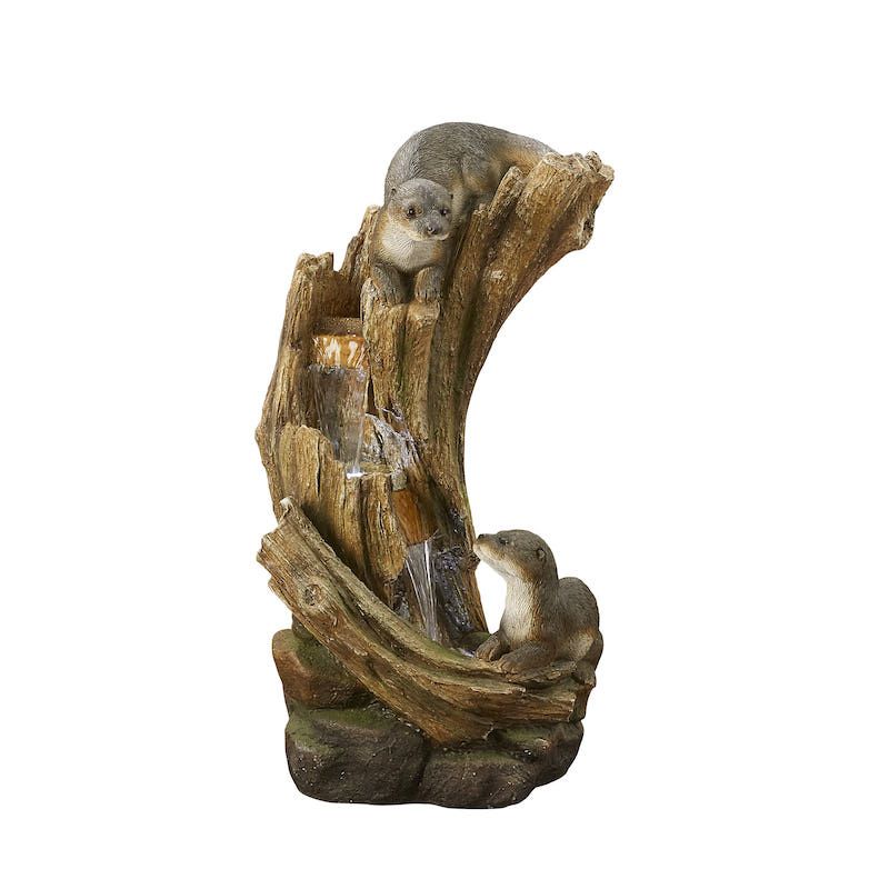 Otter fountain. Three otter figurines on a faux log. Water flows down the log into a small pool.